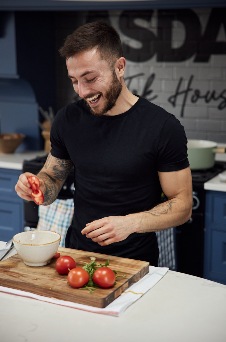 Max smiling while preparing fresh tomatoes in his kitchen